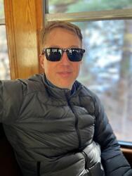 A man with sunglasses in a gray puffy coat