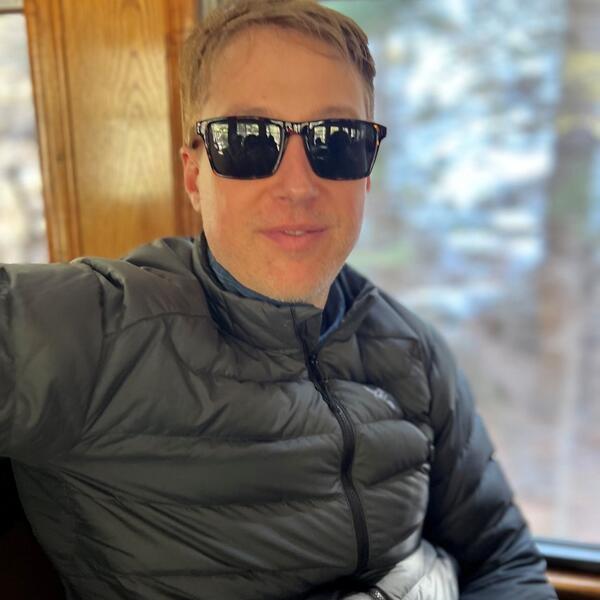 A man with sunglasses in a gray puffy coat